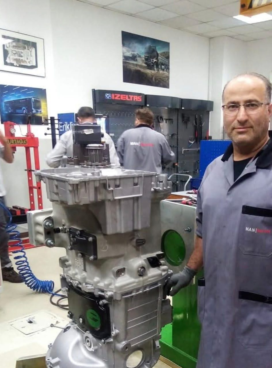 Habib Rad with a rebuilt truck transmission in a training workshop